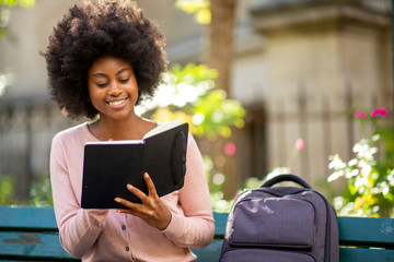 young smiling african american woman reading book outside