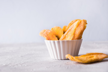 Dehydrated and dried mango chips in white bowl. Close up.