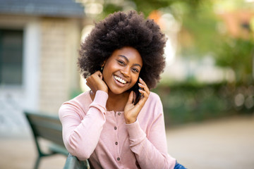 Close up smiling young african american lady with afro hair talking with mobile phone