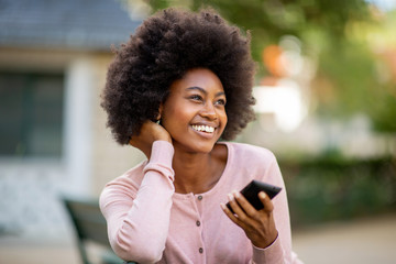Close up smiling young african american lady with afro hair with mobile phone