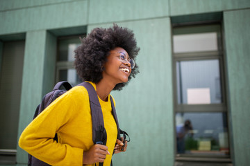 Fototapeta na wymiar Side happy black female college student with glasses and bag