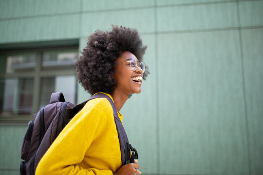 Side happy african american female college student with glasses and bag
