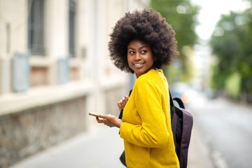 african american woman with bag and mobile phone walking in city