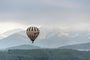 A hot air balloon flies over a sea of clouds in the region of La Garrotxa, in Girona (Spain) at dawn.