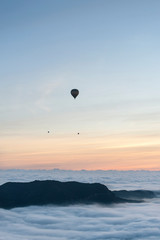 A group of hot air balloons flies over a sea of clouds in the region of La Garrotxa, in Girona (Spain) at dawn.