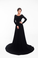 Naklejka premium Beautiful elegant young woman with fashion hairstyle and makeup posing on a white background on high heels isolated in a black long evening dress. Free space for text mockup