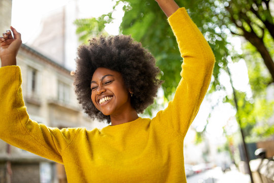 fun young afro american woman laughing with arms raised