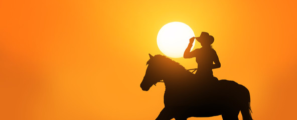 young cowgirl riding her horse at sunset © ginettigino