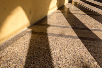 Arched passageway (arcade) in Bologna, Italy: columns are casting long shadows on terrazzo floor...