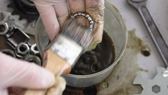 Closeup of a hand in gloves is cleaning bike parts from old grease. Wash the components of the rear hub of the bicycle wheel with cleaning fluid and brush.