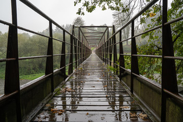 Metal bridge in the rain with diminishing perspective. Steel construction.