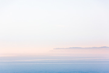 Minimalist landscape scene of Sandwich Bay, Kent on a misty but bright summer morning. The town of...