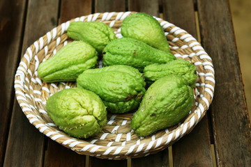 Chayot, mexican cucumber in a low wicker basket on a wooden table