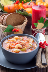 Soup with turkey, pasta, carrot, celery, tomato and cannellini beans, garnished with parmesan cheese, on the table with autumn decoration, reflecting the US Thanksgiving harvest feast,  vertical