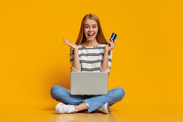 Excited girl using laptop and credit card for purchasing online