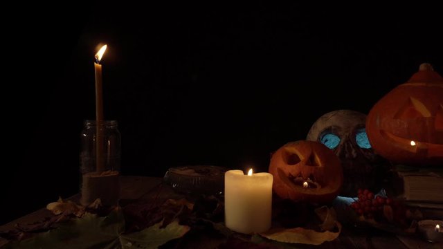 Halloween decorations two pumpkin lanterns and a human skull in candlelight, loop video. Theme of autumn holidays, traditions on Halloween. Craft handmade pumpkin for decoration. Video can be looped.