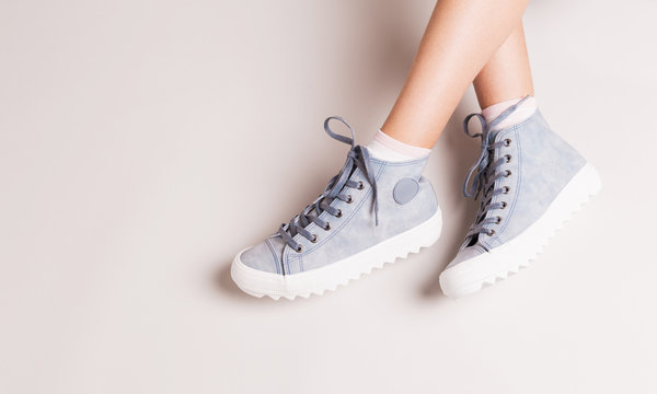 Pastel blue sneakers on crossed legs - casual footwear