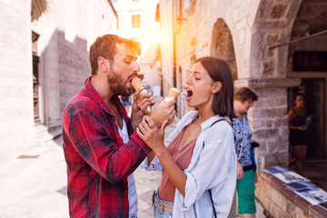 Boyfriend eating ice cream with girlfriend on a street
