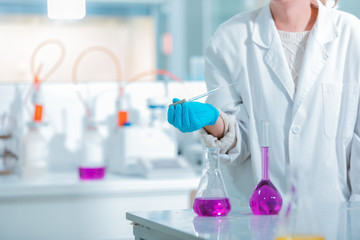 Fototapeta premium Young medical technologist female making testing with test tube while doing research in science laboratory. Science, chemistry, technology, biology and people concept.