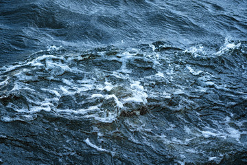 Fototapeta premium Aerial view to ocean waves. Blue water background. Abstraction of sea foam in the ocean. Dark water, storm waves