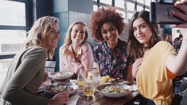 Four Female Friends Posing For Selfie In Restaurant Before Eating Meal