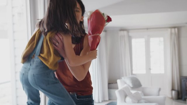 Daughter Running To Mother And Handing Her Bunch Of Flowers To Celebrate Birthday Or Mothers Day