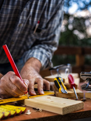 Adult carpenter craftsman with a pencil and the carpenter's square trace the cutting line on a wooden table. Construction industry, housework do it yourself. Stock photography.