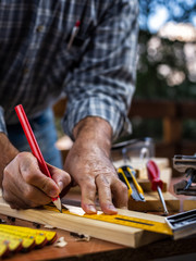 Adult carpenter craftsman with a pencil and the carpenter's square trace the cutting line on a wooden table. Construction industry, housework do it yourself. Stock photography.