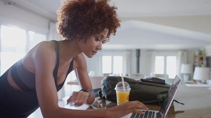 Young Woman Downloading Data From Personal Health Tracker To Laptop After Exercise - Powered by Adobe