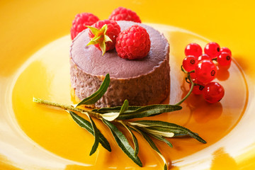 Tasty dessert cheesecake with raspberries and currants on a yellow background. 