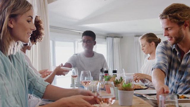 Group Of Young Friends Sitting Around Table At Home Enjoying Meal Together