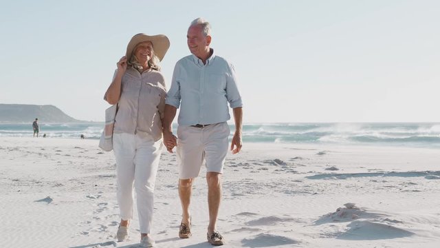 Senior Couple Walking Along Beautiful Sandy Beach On Summer Vacation 