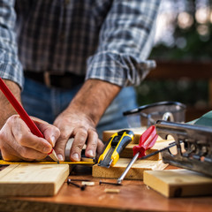 Adult carpenter craftsman with a pencil and the carpenter's square trace the cutting line on a wooden table. Construction industry, housework do it yourself. Stock photography.