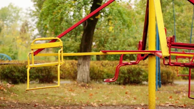 motion of an empty children's carousel. the carousel moves at a minimum speed clockwise and stops. autumn. full hd, no sound.