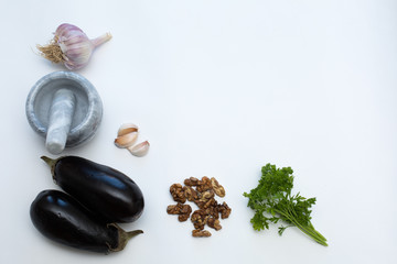 Mortar and pestle, garlic, vegetables and nuts on a white background