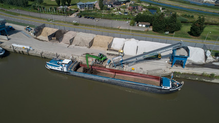 Obraz premium Loading barge with sand and rubble on a small berth. Freight transport logistics