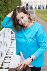 Portrait of business woman straightens hair and holding her bag, blue blouse, looking at camera