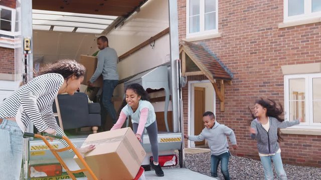 Family Unloading Furniture From Removal Truck Into New Home