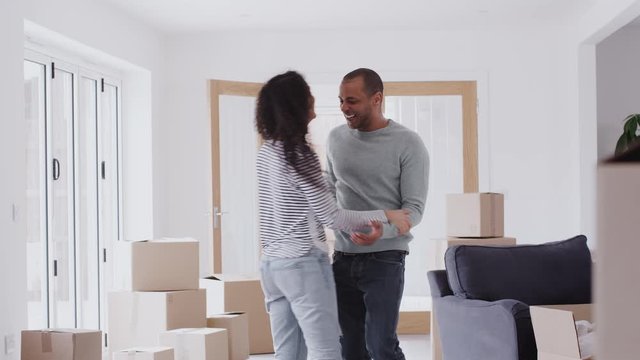 Loving Couple Dancing Together As They Celebrate Moving Into New Home 