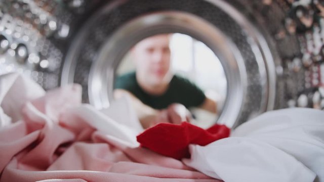 Young Man Taking Out Red Sock Mixed With White Laundry From Washing Machine
