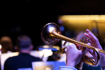 A trumpet player playing on a gold plated matte lacquered trumpet during a performance with other...
