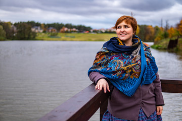 Fat girl thought on the lake, cloudy weather, in a beautiful scarf