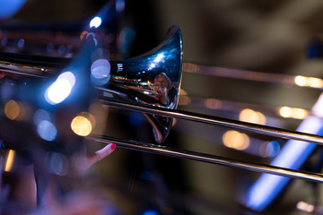 Obraz na płótnie Canvas A female musician with red lacquered fingernails playing the trombone in a big band setting during a performance