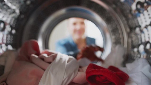 Young Woman Taking Out Red Sock Mixed With White Laundry From Washing Machine