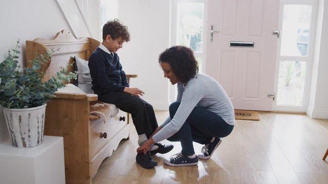Single Mother At Home Getting Son Wearing Uniform Ready For First Day Of School