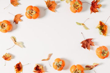 Obraz premium Autumn creative composition. Dried leaves, persimmon on white background. Fall concept. Autumn background. Flat lay, top view, copy space