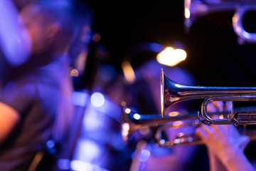 Trumpet players of a big band section playing their horns in blue stage lighting