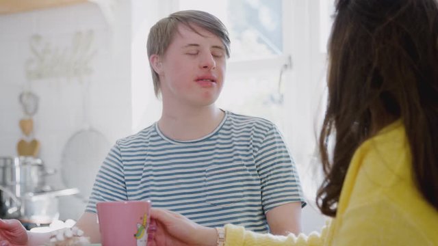 Young Downs Syndrome Couple Enjoying Hot Drink In Kitchen At Home