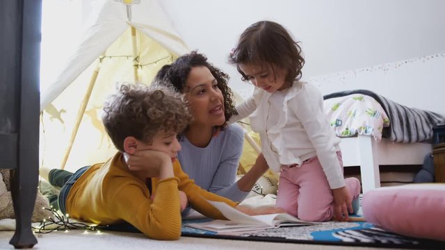 Single Mother Reading With Son And Daughter In Den In Bedroom At Home