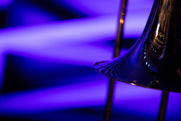A moody photo of a bell of a trombone in blue stage lights